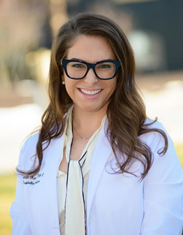 A smiling healthcare professional wearing glasses and a white coat.